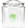A clear glass dog treat  jar with a lid, featuring a green logo that reads 'Green Juju'