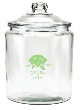 A clear glass dog treat  jar with a lid, featuring a green logo that reads 'Green Juju'
